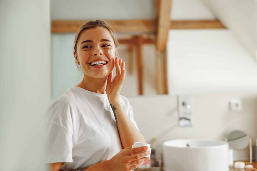 Woman smiling and applying face cream after dermaplaning treatment in Ashburn, VA